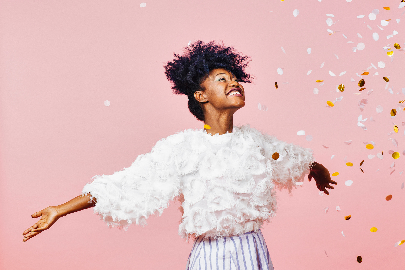 Young woman celebrating happiness with a big smile throwing confetti